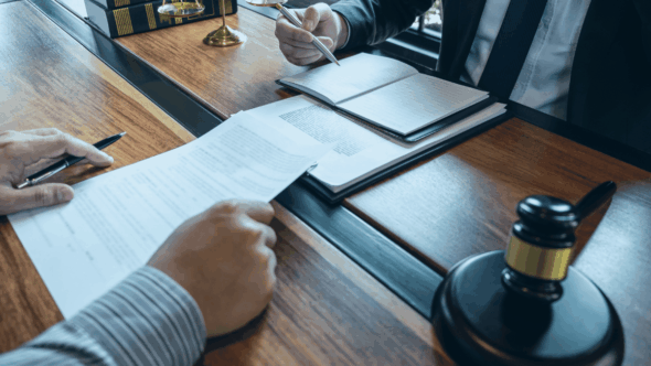 An attorney and client sitting at a desk discussing patent infringement case