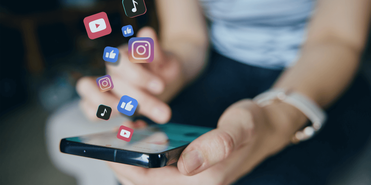 Person using a smartphone with social media app icons floating above, representing online sharing and copyright considerations for businesses.
