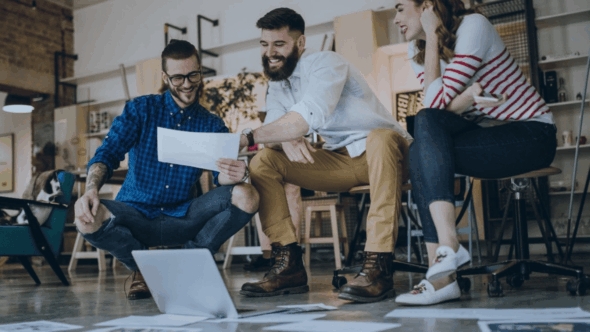 Three inventors reviewing documents while preparing a patent application